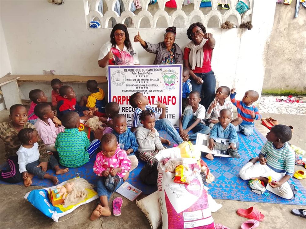 Remise de dons à l’orphelinat NAFO, à Douala : l’équipe de l’association et les enfants réunis derrière la banderole de l’établissement.